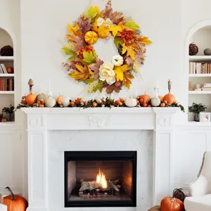 Autumn wreath with maple leaves and pumpkins hanging above a white fireplace mantel