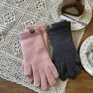 Close-up detail of winter warm knitted wool gloves in pink and grey with cute bear tags.