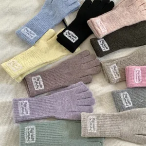 Close-up detail of multi-color knitted gloves with decorative lace cuffs, soft woolen fabric.