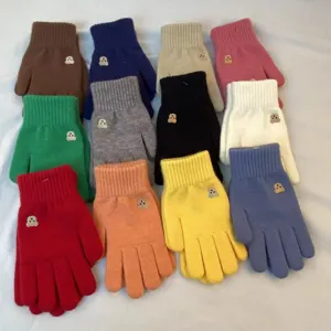 Close-up of cozy knitted winter gloves featuring cute bear patch details and solid colors.