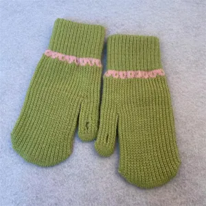 Green knit wool gloves close-up showing pink wave cuff detail and warm winter fingerless design.