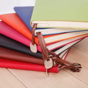 Colorful A5 leather hardcover notebooks stack detail with ribbon bookmarks and metal pendants.