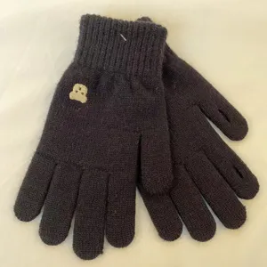 Detailed view of black winter knit gloves featuring cute bear embroidery and soft warm fabric.