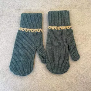 Close-up of winter knit gloves, dark cyan color with cozy textured pattern detail.