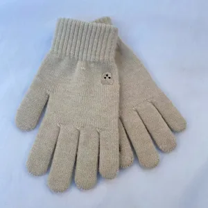 Close-up detail of cute knitted winter gloves in beige with a sweet small bear embroidery.