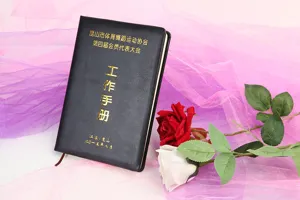 Cuaderno profesional de cuero sintético negro con detalles dorados, vista de detalle cercana.
