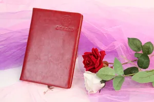 Cuaderno de negocios de cuero rojo con emblema grabado y cinta marcapáginas, detalle.