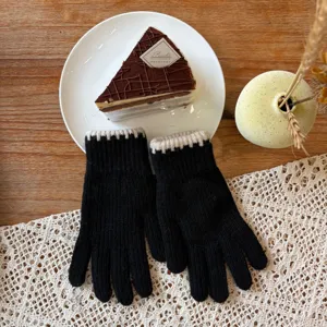 Detailed view of cozy black knit gloves with contrasting beige cuffs on a rustic table.