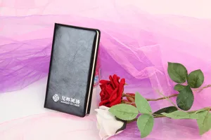 Detalle de la cubierta del cuaderno de cuero PU negro con logotipo y textura fina.