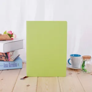 Detailed shot of a light green leather notebook on a wooden table with cozy desk decor.