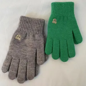 Close-up detail of winter warm knitted gloves with cute bear embroidery, soft knit fabric.