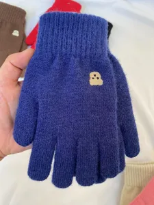 Detailed view of winter warm knit gloves in blue color featuring cute bear embroidery design.