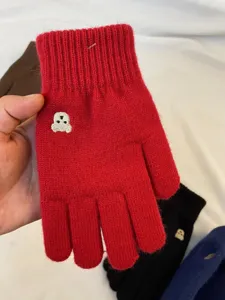Close-up detail of winter warm knit gloves featuring cute bear embroidery and soft fabric.