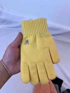 Close up of cute yellow knit touchscreen gloves with lovely bear embroidery detail.