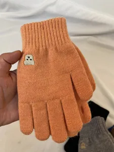 Detail view of winter warm knitted gloves with cute bear embroidery and finger openings.
