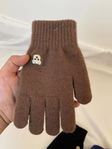 Close-up of brown knitted winter glove featuring a cute embroidered bear pattern, soft and warm.