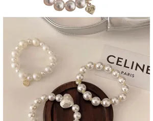 Detailansicht eleganter Perlenhaargummis und Armbänder mit Herzanhängern