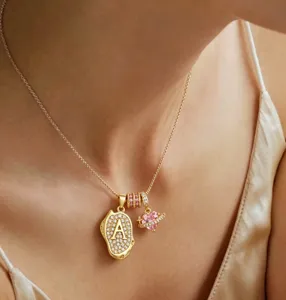Detailansicht der goldenen Kette mit ovalem Buchstaben-A und rosa Herz-Anhänger.