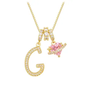 Detailansicht der goldenen Initiale G und des rosa Herzanhängers mit Zirkonia-Steinen