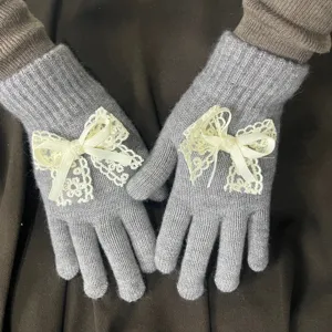 Nahaufnahme der grauen Strickhandschuhe mit eleganten beige Schleifen und Perlen.