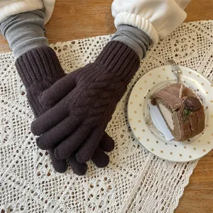 Vue détaillée de gants en tricot marron épais sur une nappe en dentelle cosy pour hiver.