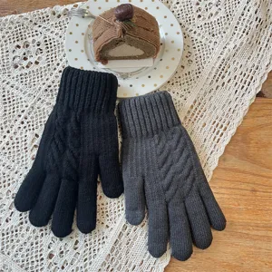 Gros plan de gants tactiles tricotés d'hiver en noir et gris foncé avec poignets côtelés.