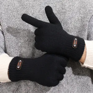 Gros plan sur les gants tricotés pour hommes en laine noire texturée avec un écusson élégant.
