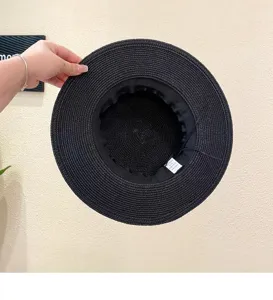 Detailed view showing the inner straw weave, adjustable band, and size label of the black hat.