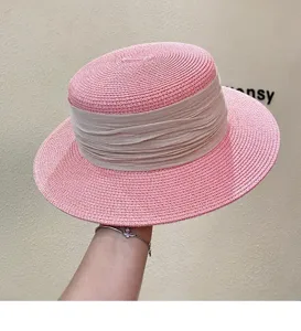 Detail view of a pink straw hat with a beige ribbon, elegant sun protection and beach style.