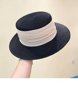 Detail shot of a black straw hat with a wide beige ribbon, summer sun protection.