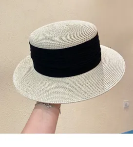 Close-up detail of a classic flat-top woven straw hat with a wide brim and elegant black ribbon.