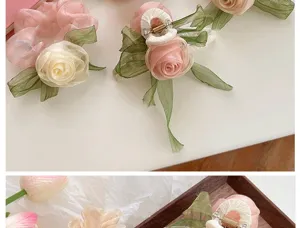 Macro view of elegant organza rose flower hair scrunchies and matching claw clips set.