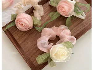 Close-up of elegant rose-themed scrunchies and hair claw on a wooden tray