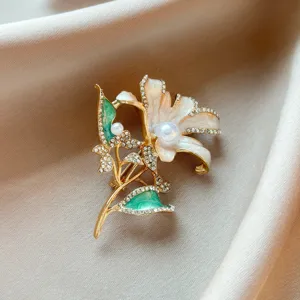 Elegant lily brooch detailed close-up featuring sparkling rhinestones, pearls and enamel design.