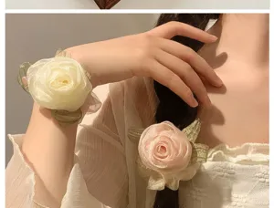 Close-up of elegant rose flower hair scrunchies in cream and pink on a model.