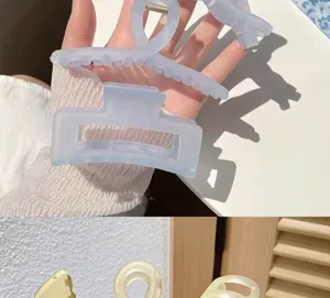 Gros plan d'une grande pince à cheveux mate couleur gelée tenue dans une main d'une personne
