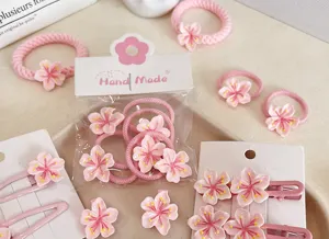 Detailed view of handmade pink cherry blossom hair ties and resin clips in packaging