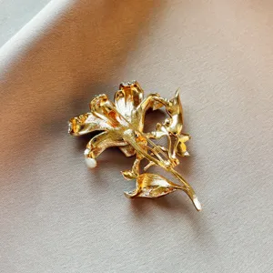 Gold tone lily flower brooch detail view, exquisite metallic texture and crystal pin back.