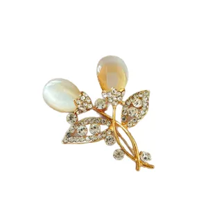 Elegant gold-tone rhinestone and cat's eye stone flower brooch, chic suit coat accessory for women.