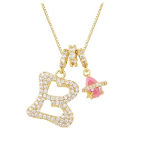 Detailed shot of a gold-plated letter B and pink planet pendant with clear zircons.