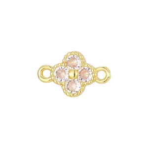 Macro view of a gold clover charm with four pink zircons for DIY jewelry making.