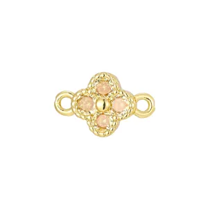 Detailed macro view of a gold-plated four-leaf clover charm with peach zircon stones.