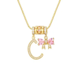 Nahaufnahme der goldenen Halskette mit Zirkonia-Buchstabe C und rosa Herzschleife