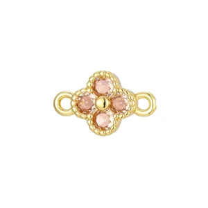 Close-up of a gold-plated four-leaf clover charm with pink cubic zirconia stones.
