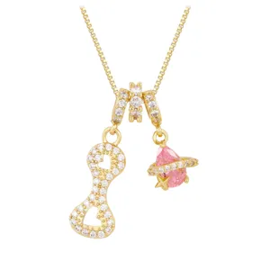 Macro detail view of gold heart pendant with zircons and pink planet charm on necklace