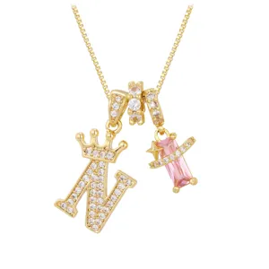 Detailansicht einer Goldkette mit gekröntem N-Anhänger und rosa Zirkon-Elementen.