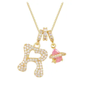 Macro view of gold-plated heart initial R necklace with sparkling pink planet charm