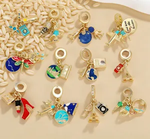 Detailed macro view of gold-plated travel-themed enamel charms on a textured grain background.