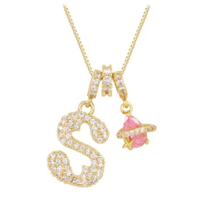 Detailed view of a gold-plated letter S necklace with pink planet charm and zirconia