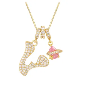 Detailed view of a gold necklace featuring a zircon-paved letter V and a pink planet charm.